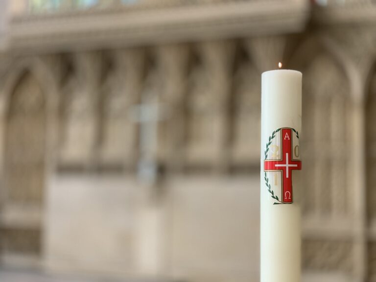 Burning candle with red cross