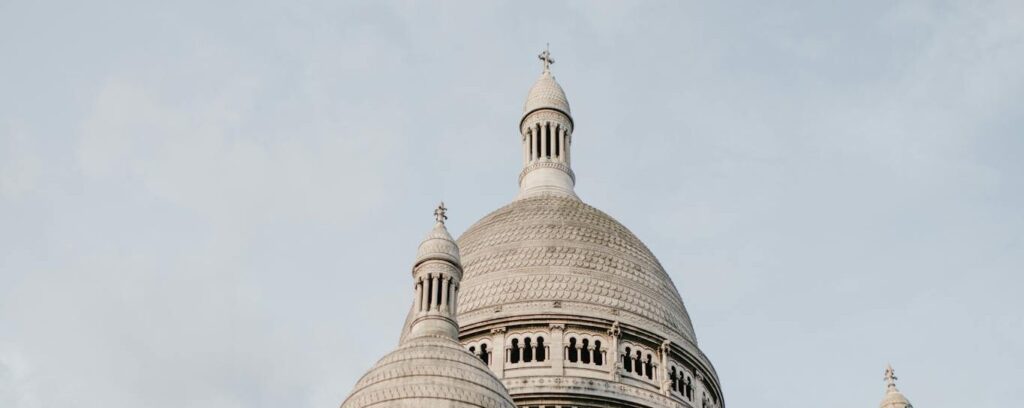 From below of famous historic building of Basilica of Sacre Coeur with high domes in Paris